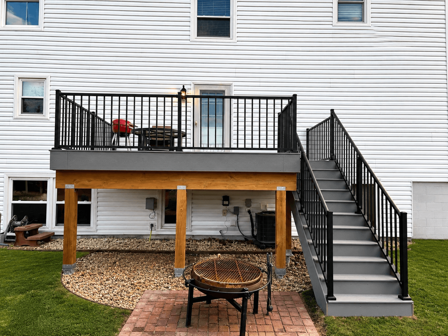 Raised deck and staircase with black railings viewed from the yard